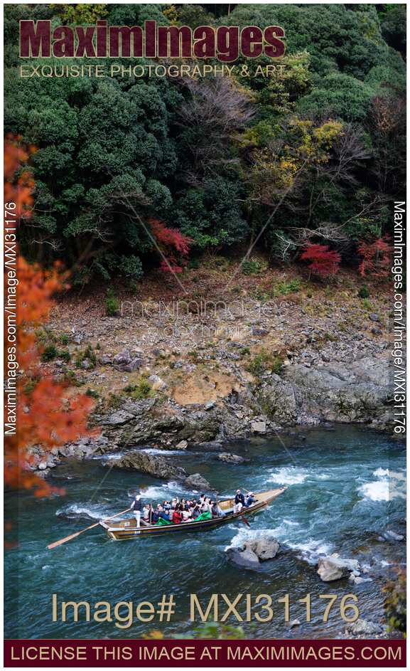 Tourists on Hozugawa river sightseeing cruise boat ride in autumn scenery of Hozukyo Ravine