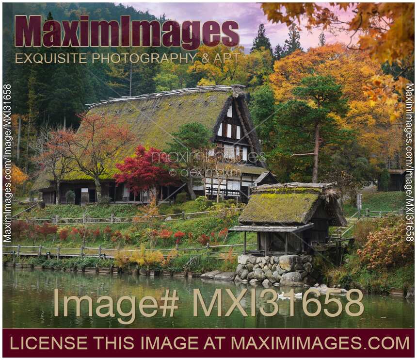 Traditional Japanese farm house and a water mill on a pond at Hida Folk Village Japan in autumn scenery