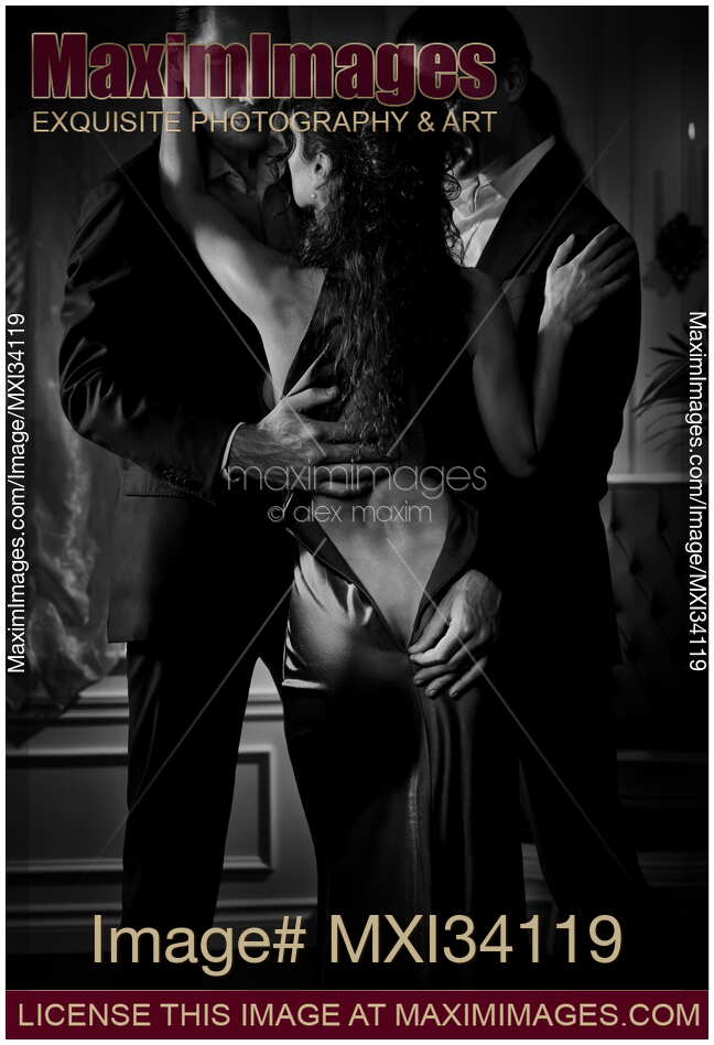 Two elegant men seducing a beautiful classy lady in open back dress. Ménage a trois, suggestive romantic black and white photo.