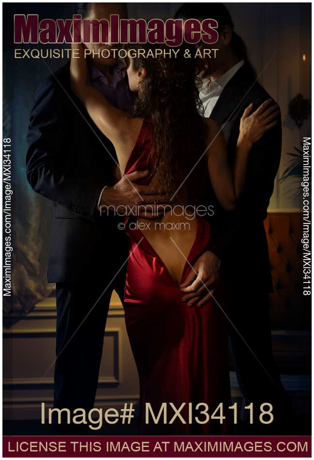 Two elegant men seducing a beautiful classy lady in red evening dress. Ménage a trois, suggestive romantic photo.