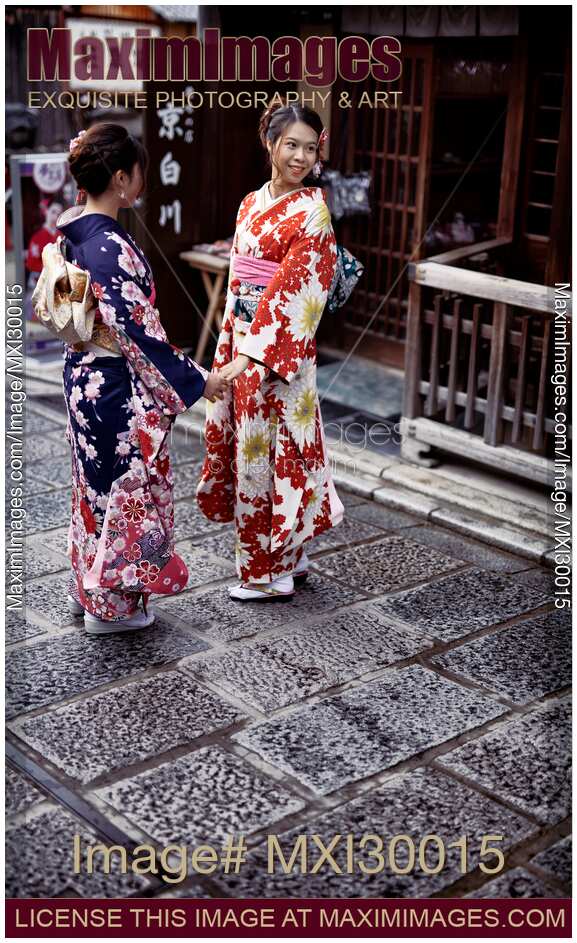 Two girls in bright Yukatas posing for a photo on a Kyoto street