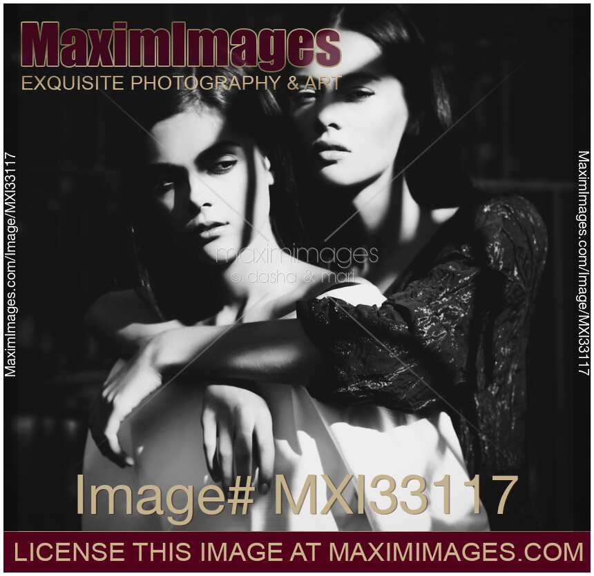 Two ladies together. Woman standing behind another embracing her. Vintage stylized dramatic portrait.