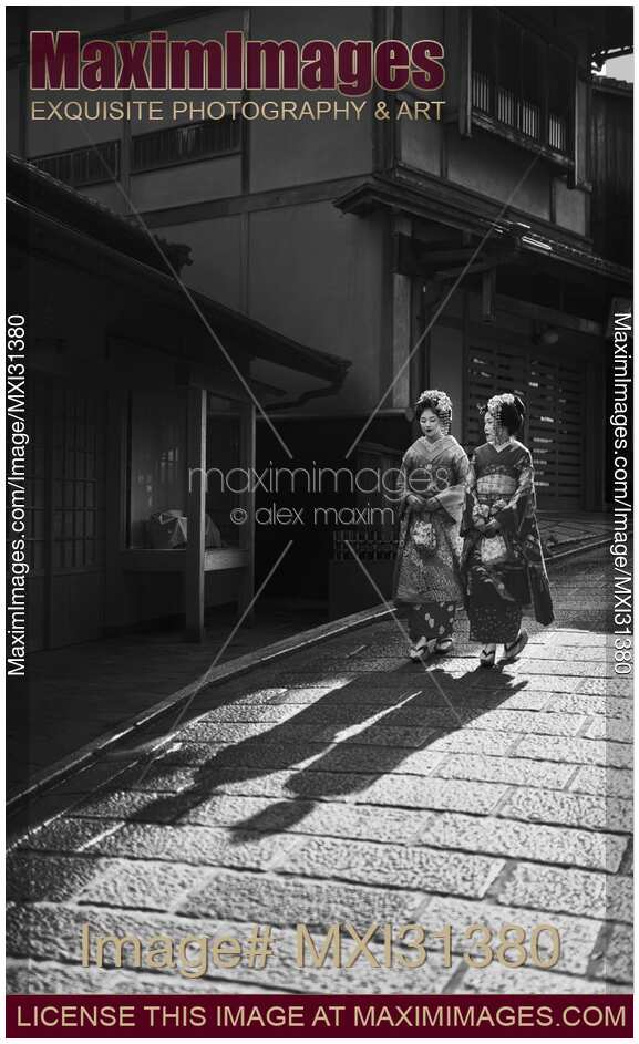 Two Maiko in kimono walking down an old street in Kyoto Japan Black and white