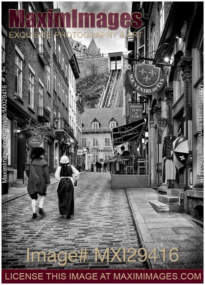 Two persons dressed in medieval costumes walking up the Rue Sous Le Fort street in old Quebec City Black and white