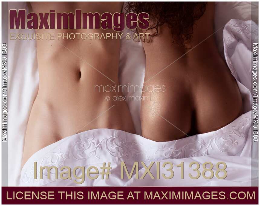 Two sexy girls interracial lesbian couple lying together in bed sensual closeup of naked bodies
