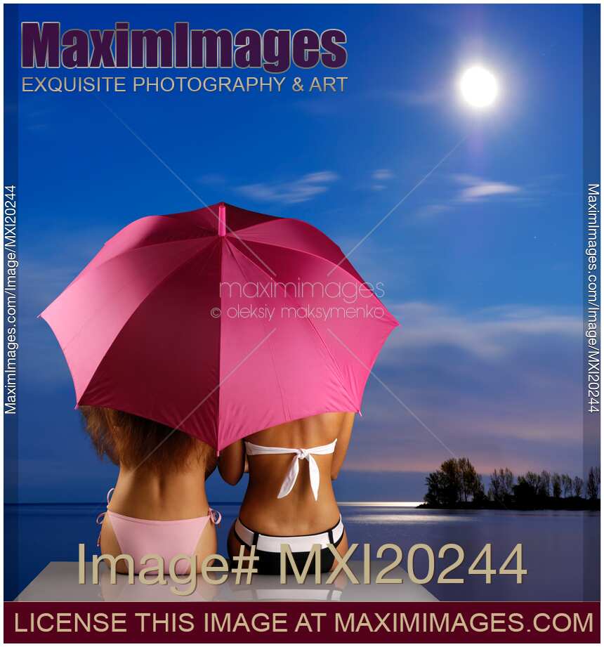 Two Women sitting together on a shore under umbrella