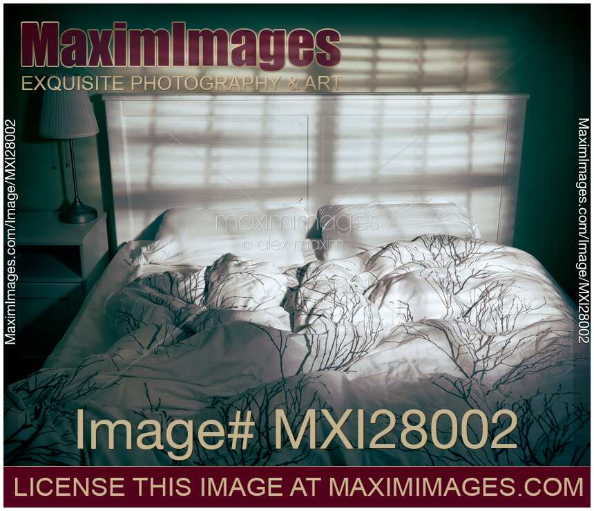 Unmade empty bed in dramatic lighting