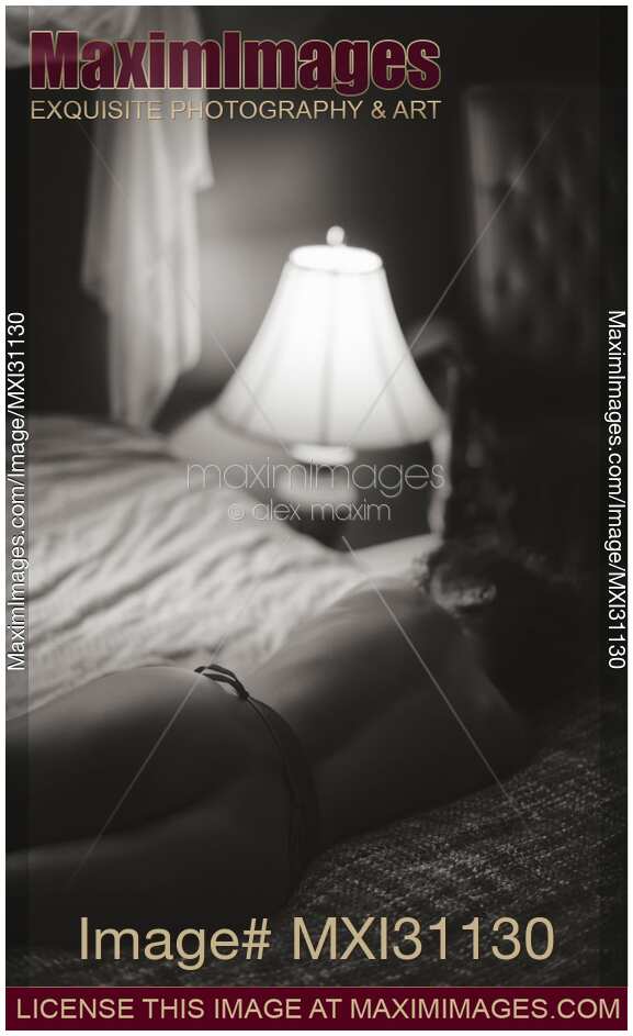 Vintage art nude portrait of the back of a beautiful naked woman lying on the bed in dim light