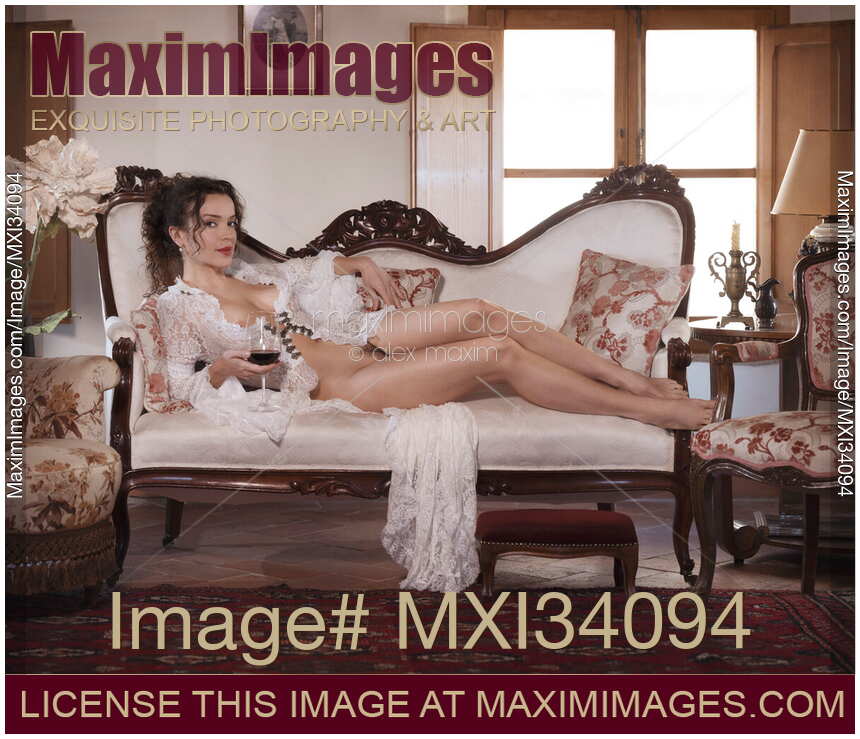Vintage erotic portrait of gorgeous seductive lady Venetian courtesan lying naked on sofa in historic house with glass of wine