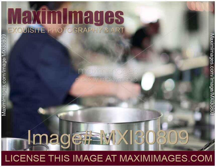 Woman Chef behind a steaming pot in a kitchen