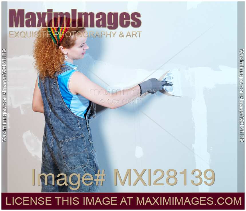 Woman construction worker patching up drywall