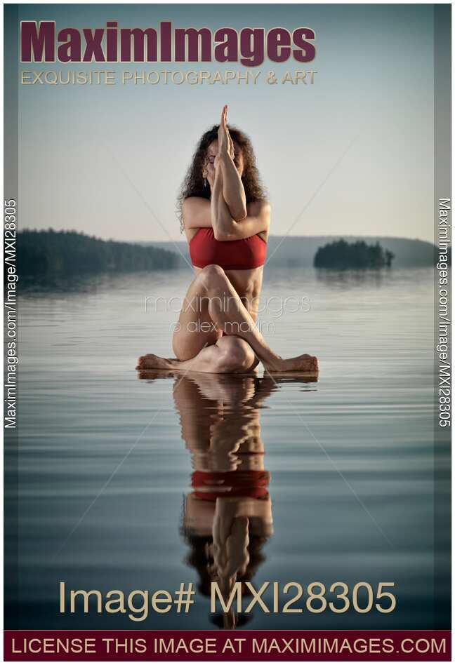 Woman doing sitting variation of yoga Eagle pose on the water