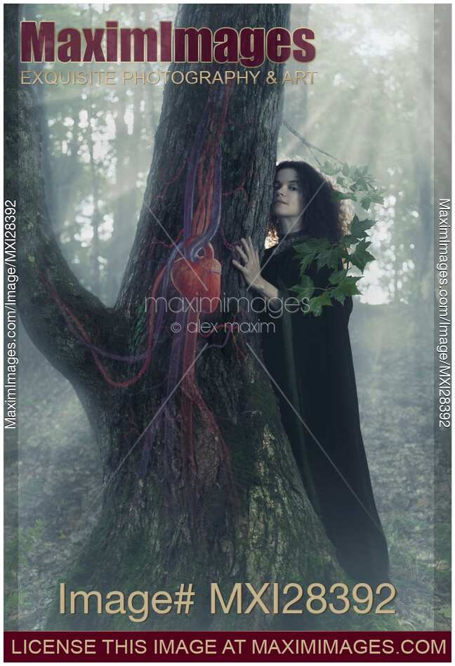 Woman druid listening to heartbeat of the tree