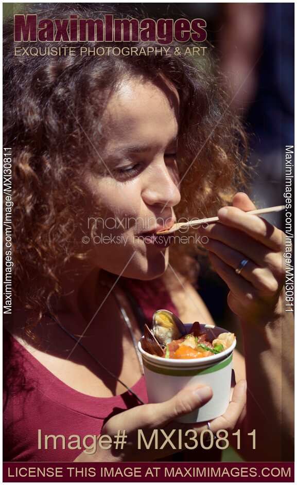 Woman eating street food enjoyment at BC seafood festival in Canada