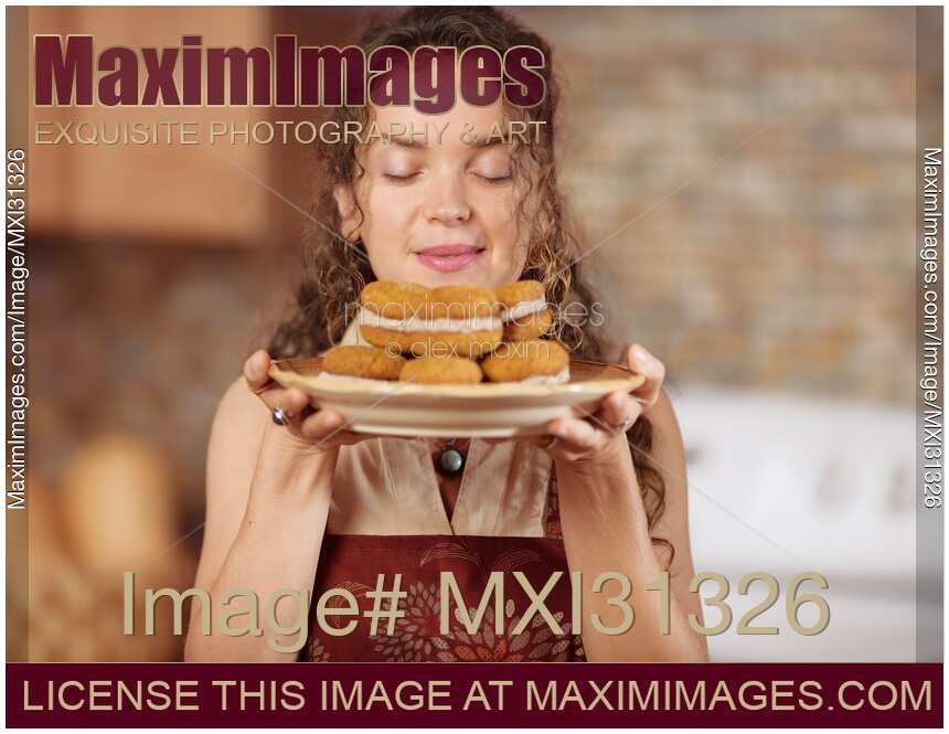 Woman enjoying smell of fresh home-made baked cookies in the kitchen