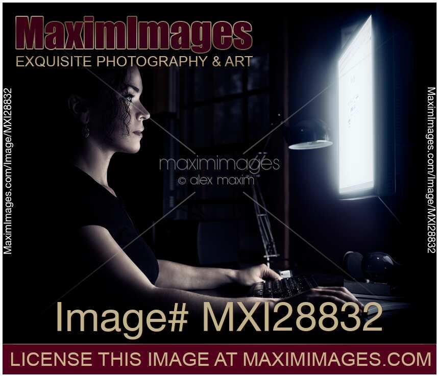 Woman face illuminated by the computer screen in dark of a night