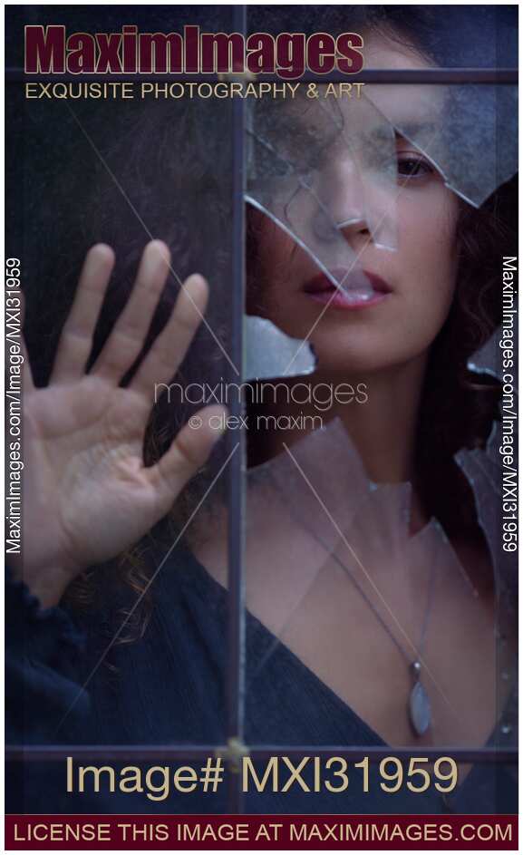 Woman face looking from behind a broken window glass drama and mystery concept