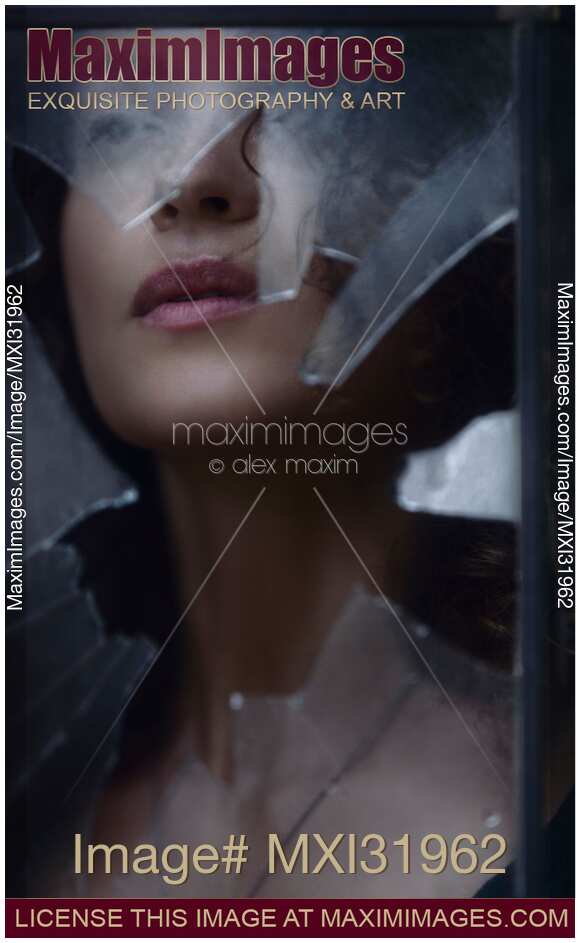 Woman face visible through a hole in a window looking through broken glass