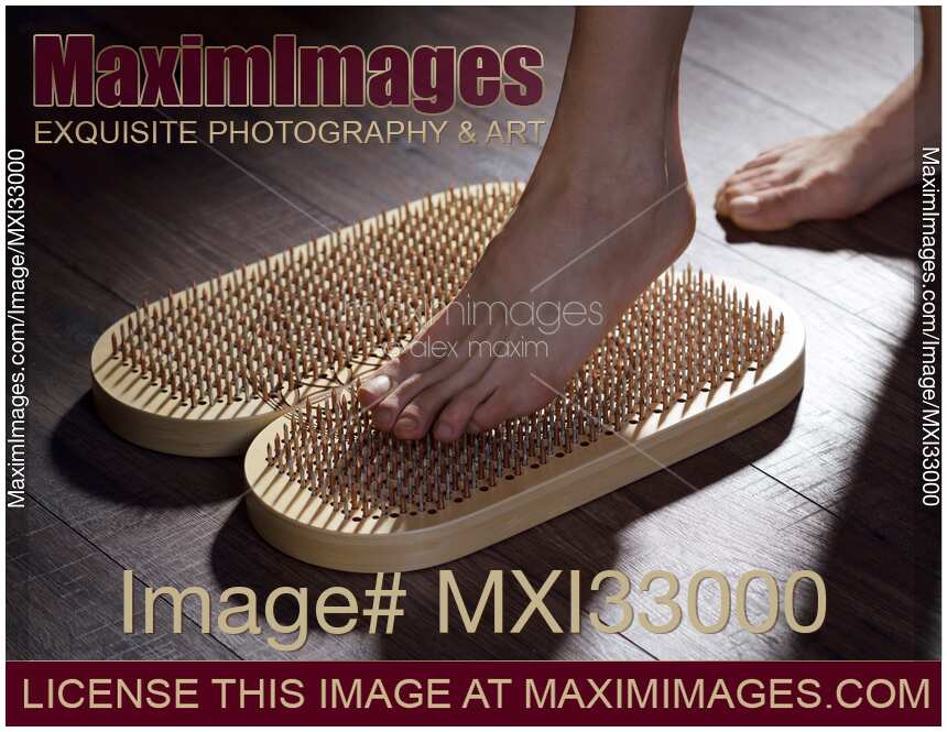 Woman foot stepping on Sadhu Board Yogic board of sharp metal nails