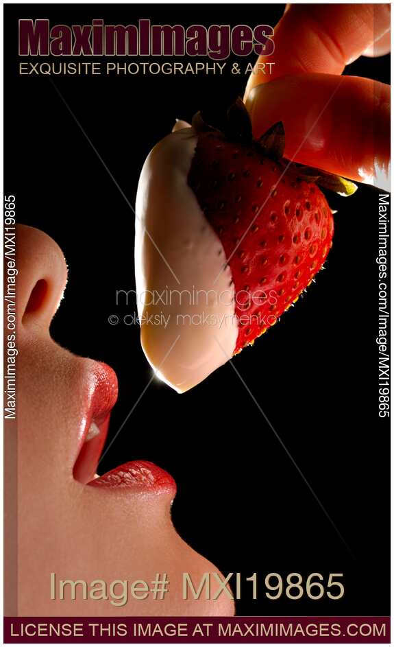 Woman holding strawberry in cream at her mouth
