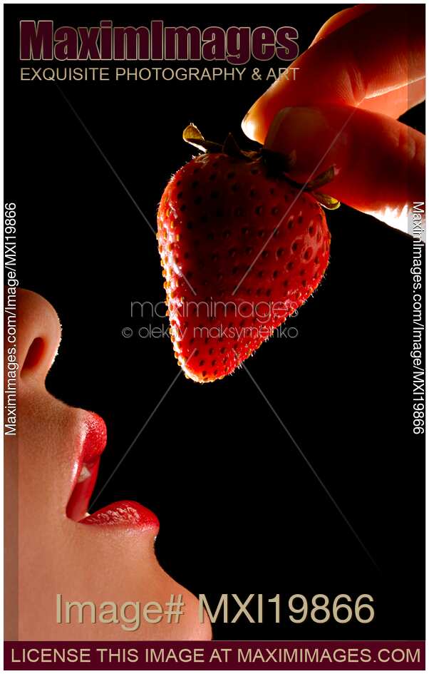Woman holding strawberry near mouth