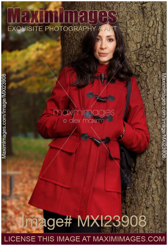 Woman in a Red Coat Leaning Against a Tree