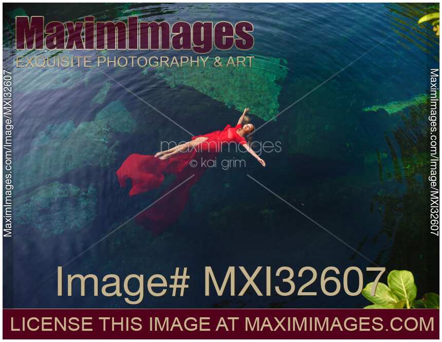 Woman in beautiful red dress lying on clear blue water Aerial fine art photograph