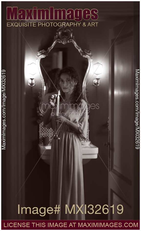 Woman in evening gown lighting a candle in her hand with a mysterious look Black and White boudoir portrait