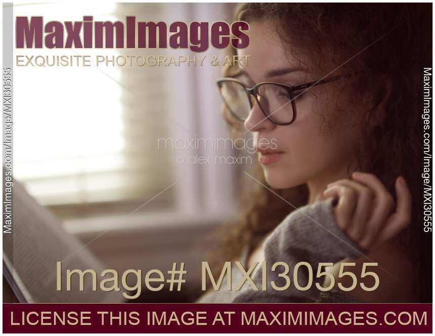 Woman in glasses reading a book by the window