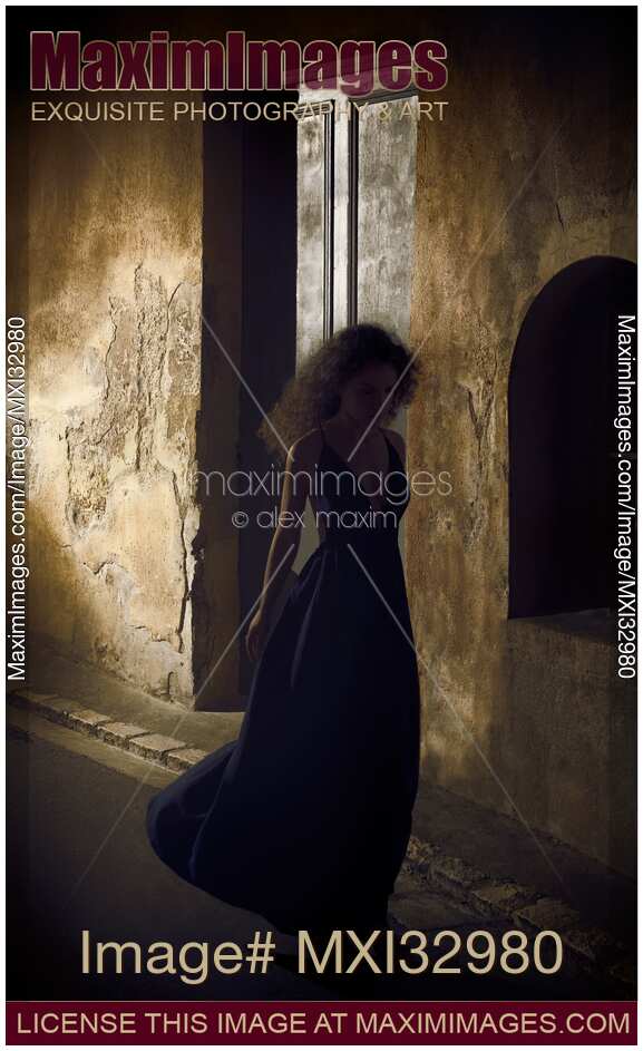 Woman in long dress walking along a shabby dark old street of European town at night Dramatic portrait France