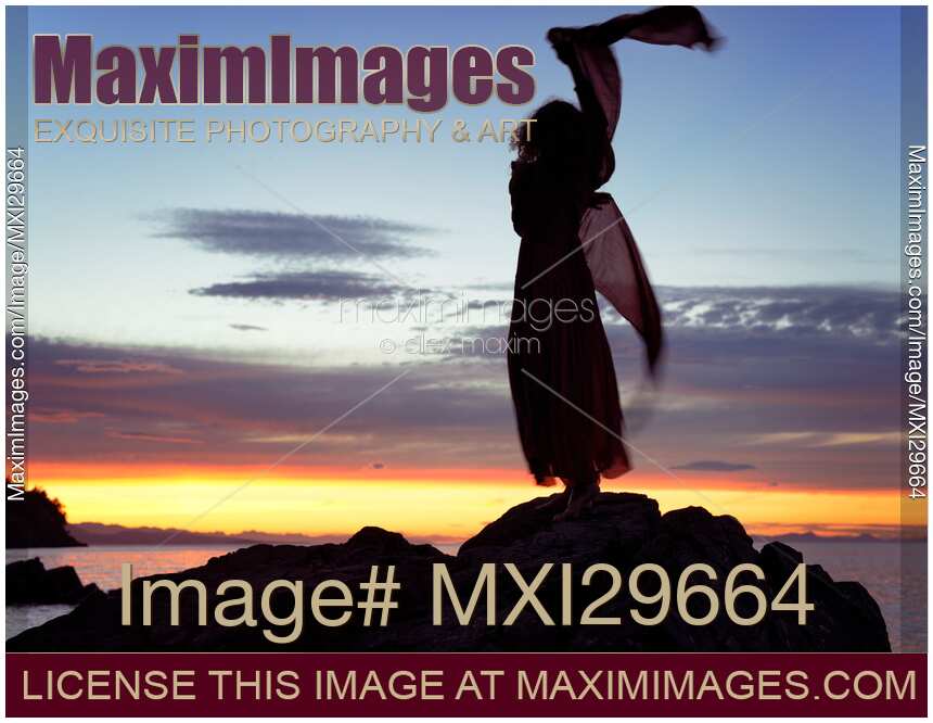 Woman in red dress flying in the wind dancing silhouette in sunset nature scenery