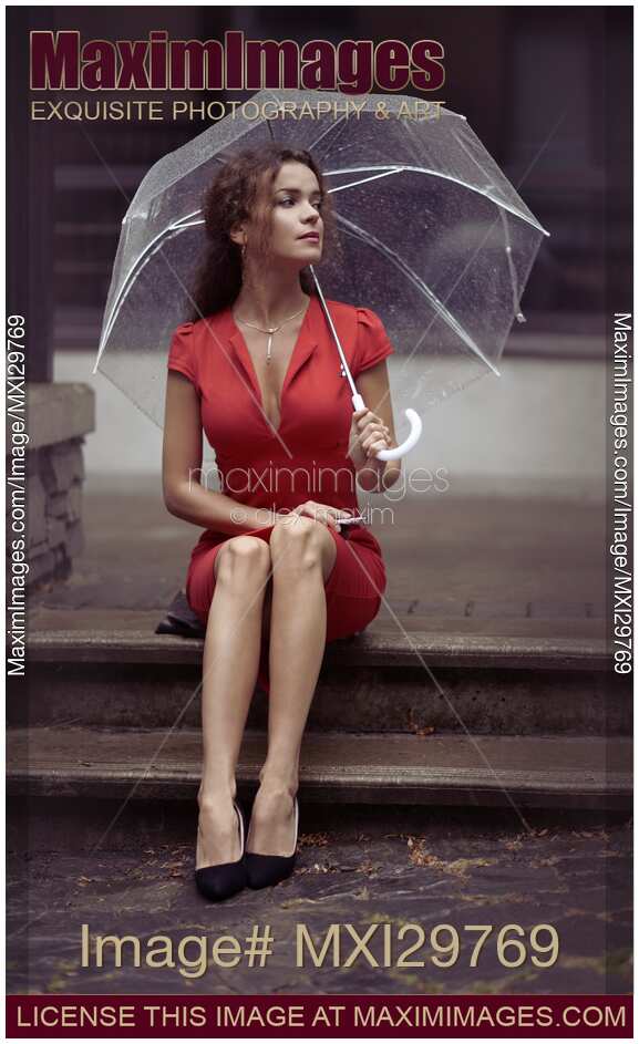 Woman in red dress sitting on the street with umbrella waiting for someone