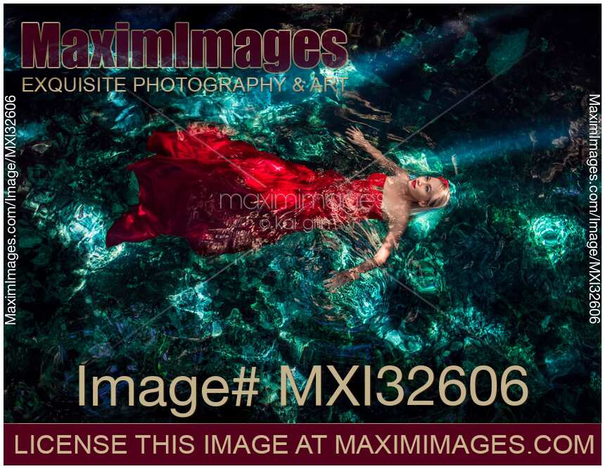 Woman in red flowy dress in clear turquoise water of a cenote Fine art photograph