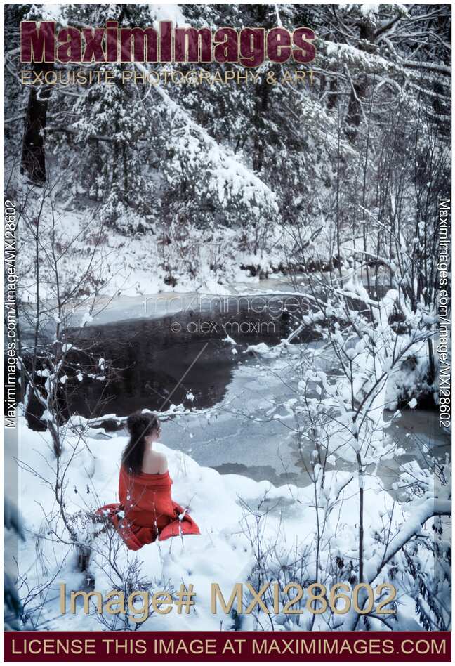 Woman in red kimono sitting in snow by a river