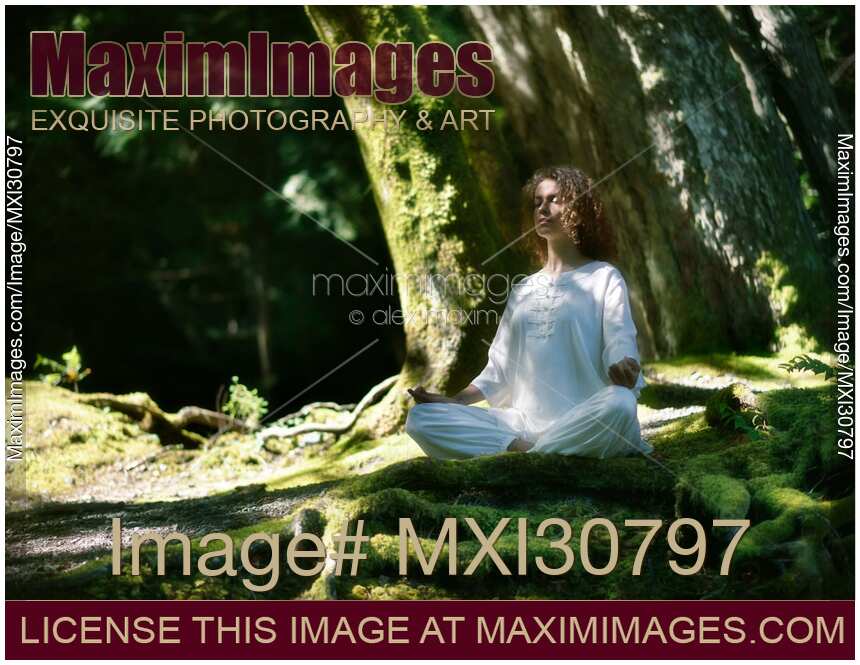 Woman in white clothes meditating in the nature in a deep green forest