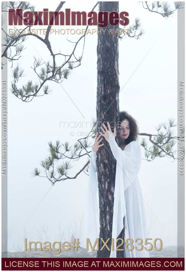 Woman in white dress hugging a tree