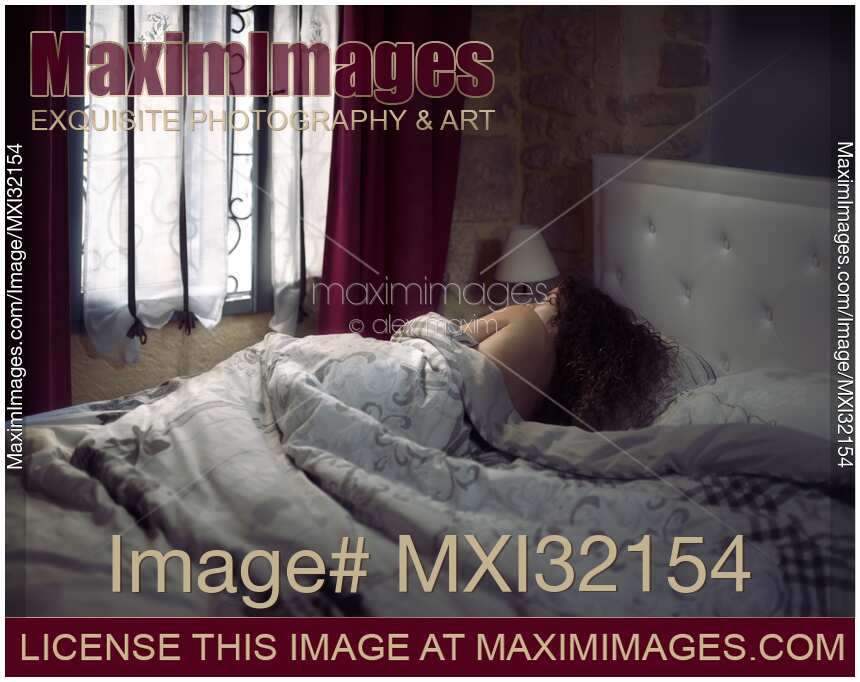 Woman lying asleep in bed in the morning covered with a blanket in a bedroom