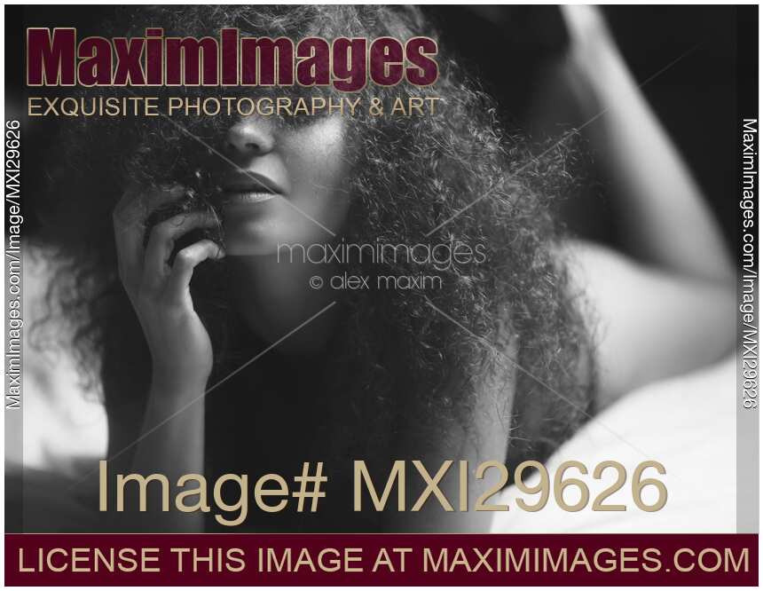 Woman lying in bed with her hair covering her face Sensual artistic black and white portrait