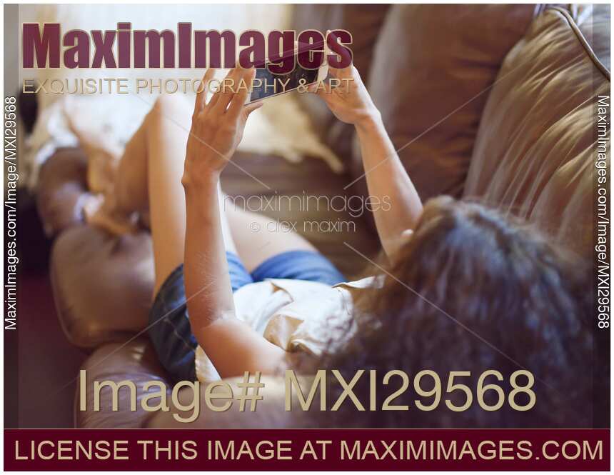 Woman lying on a sofa watching video on iPhone smartphone