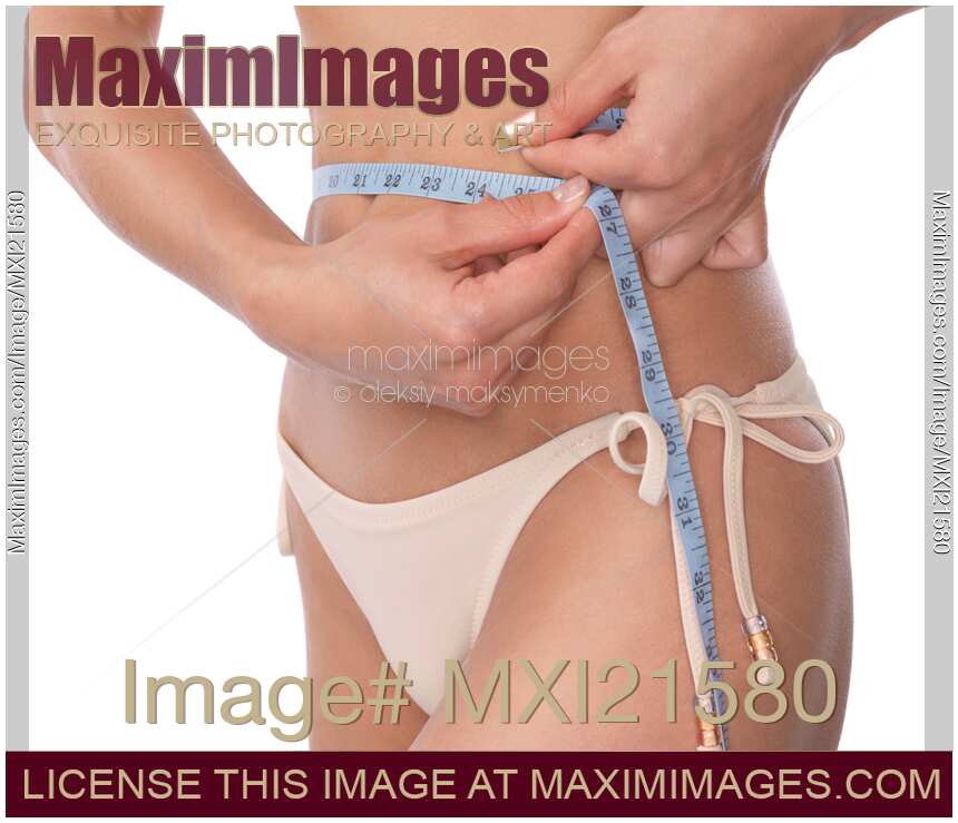 Photo of Young slim woman measuring her waist with a tape