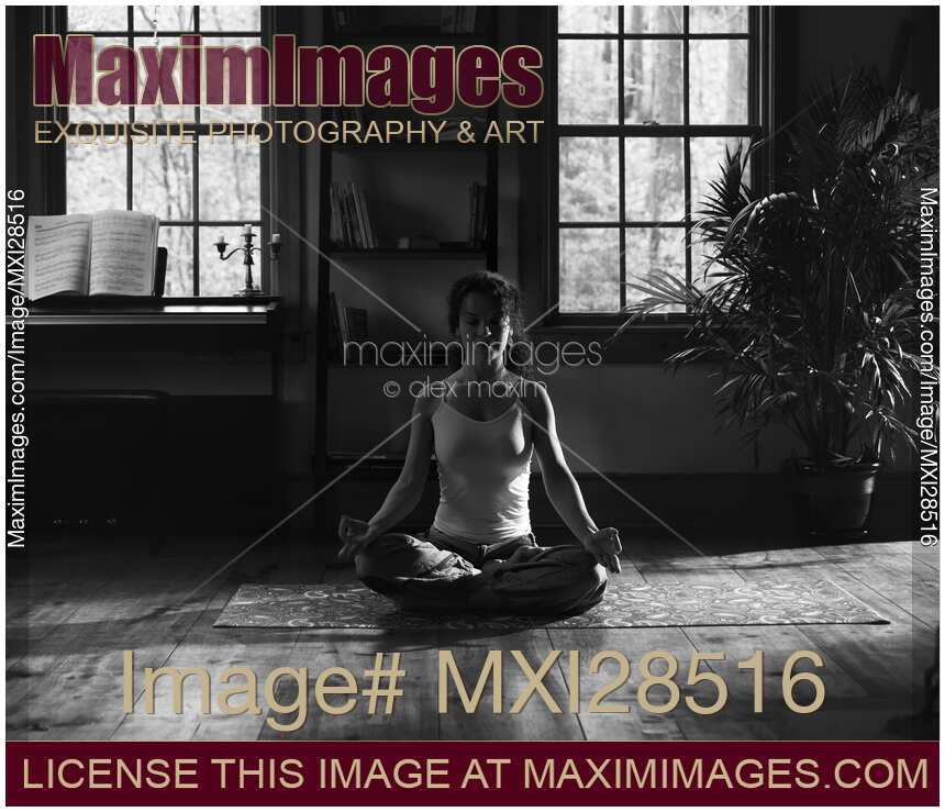 Woman meditating at home in dramatic dim light black and white