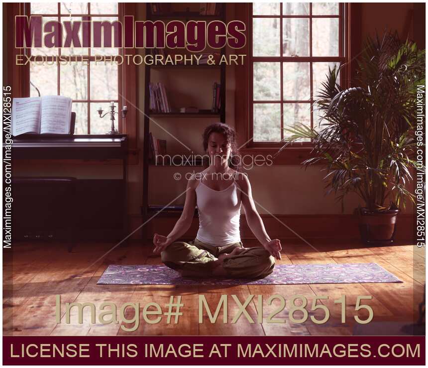 Woman meditating at home in dramatic dim light