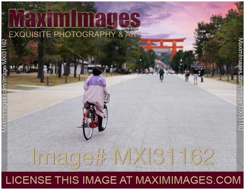 Woman on a bicycle riding towards Torii gate of Heian Shinto Shrine in Kyoto