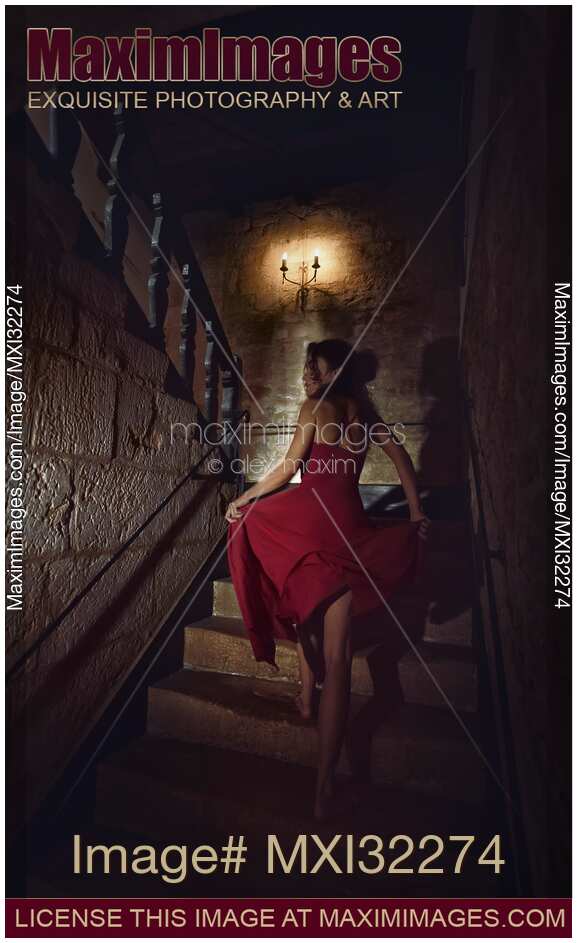 Woman on a staircase of an old house running barefoot upstairs in fear