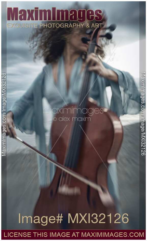 Woman passionately playing cello on ocean shore with her hair flying in the wind