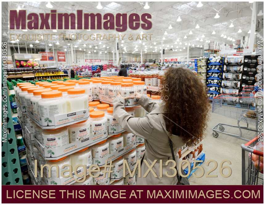 Woman picking a can of coconut oil at Costco Wholesale warehouse store food section