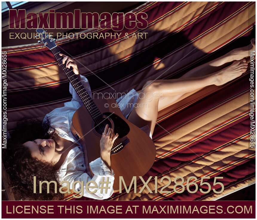 Woman playing the guitar in a hammock at home