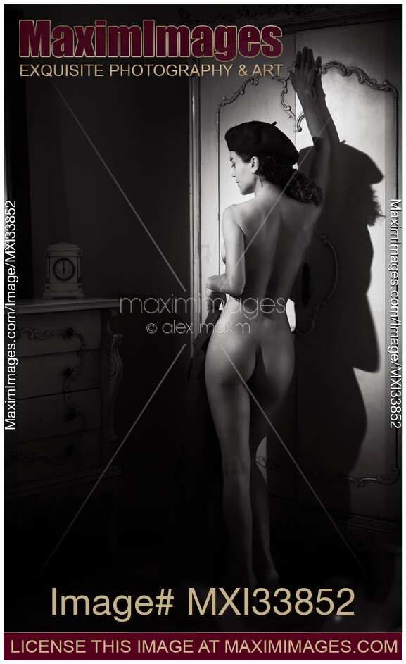 Woman posing nude leaning against an antique wardrobe revealing her beautiful sensual curves Black and white