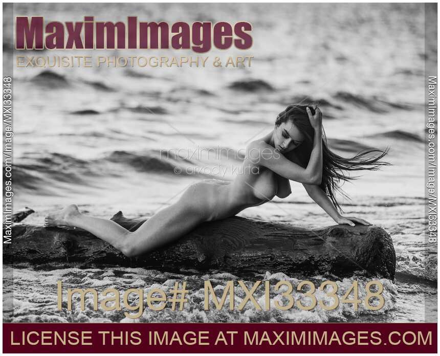 Woman posing nude on driftwood in stormy sea water Fine art nude photography