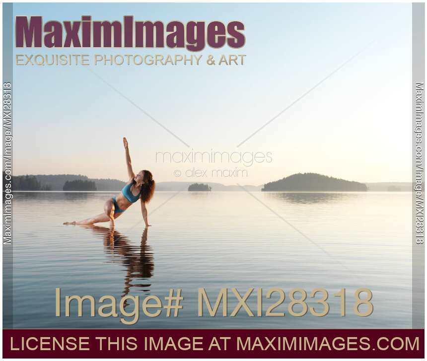 Woman practicing Hatha yoga on a platform in the water Triangle pose
